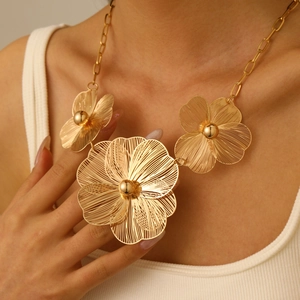 Close-up of golden hollow flower necklace with three varying sized floral pendants
