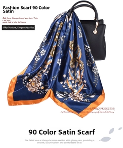 Close-up of floral satin square scarf with orange borders draped over a leather handbag