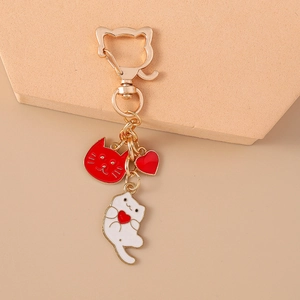 Detailed shot of golden cat keychain with red enamel kitty and heart pendants