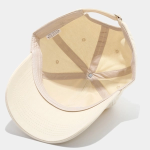 Detailed interior of beige cotton baseball cap showing seams, sweatband and 100% cotton label