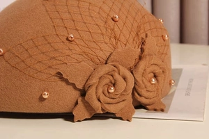 Detail of vintage brown wool beret featuring elegant mesh veil and champagne pearl accents