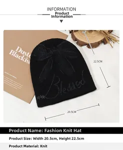 Detail view of a black knitted beanie featuring a bow design and embroidery