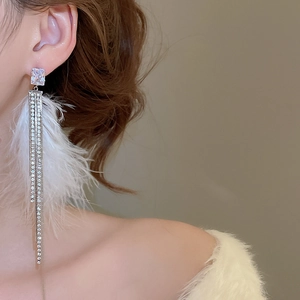 Close-up of elegant silver tassel earrings with white feathers and cubic zirconia stones