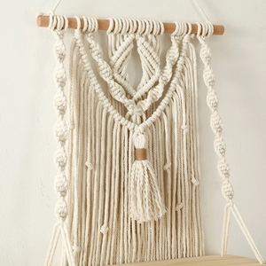 Close-up of hand-woven cotton rope knots and fringe on a boho macrame wall shelf