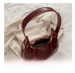 Detail of dark red crescent bag with gold zippers showing internal storage capacity