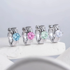 Silver stud earrings with round zircons in blue, pink, green, and white on stone surface