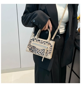 Leopard print handbag with beige trim and front zipper shown on a model in a black blazer