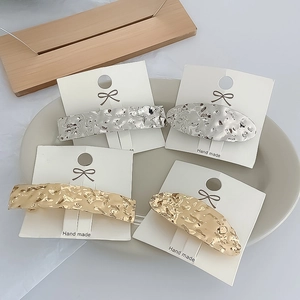 Detail of gold and silver geometric hair clips with hammered texture and handmade card