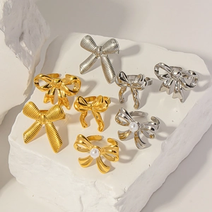 Various bow-shaped rings in gold and silver finish with pearl details on stone