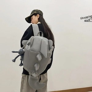 Detailed back view of a grey dinosaur backpack with creative 3D fabric scales and tail