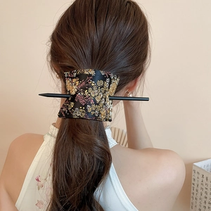 Detailed close-up of a floral fabric hair bun cuff and minimalist black hairpin accessory