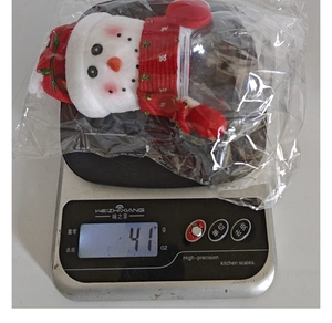 Detailed view of snowman candy jar on electronic scale showing product weight of 41g
