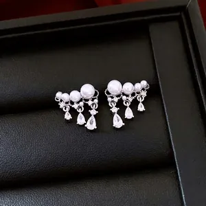 Elegant silver drop earrings with white pearls and pear-shaped zircon stones on leather