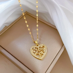Detail of gold heart pendant with tree of life design and diamonds on silk