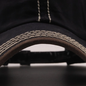 Macro detail of cotton twill baseball cap showing precise white contrast stitching on brim