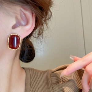 Close-up of vintage deep red acrylic square earring with gold plated metal frame on model
