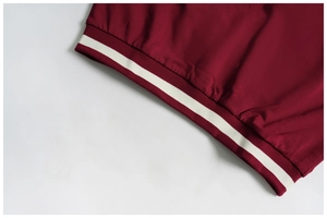 Close-up of ribbed cuffs with white stripes on a deep red athletic sweatshirt
