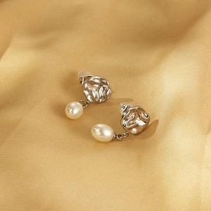 Vue macro de boucles d'oreilles en argent et perles sur un tissu en satin doré