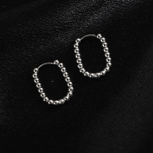 Vue détaillée des boucles d'oreilles perlées argentées sur fond de soie noire