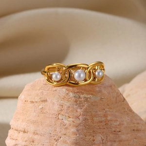 Detail showing three white pearls on a gold chain ring against a natural stone base