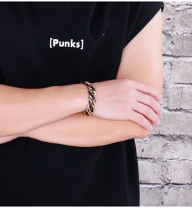 Detail of a tricolor titanium steel Cuban link bracelet in gold, silver, and black tones