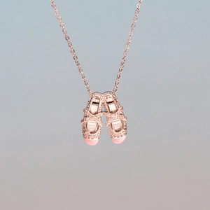 Detailed view of rose gold ballerina shoe pendant with pink accents on o-chain