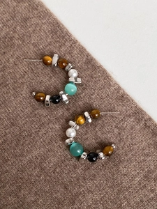 Close-up of S925 silver C-shape earrings with tiger eye stone and pearls on brown knit