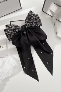 Detail of a large black bow hair clip with floral patterns and delicate white pearls