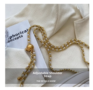 Detail of adjustable gold metal ball buckle and woven chain strap on white quilted bag