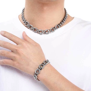 Close-up of a silver Cuban link necklace and bracelet set with clear crystal accents