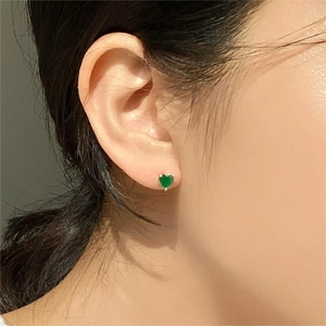 Elegant 925 sterling silver heart earrings with green zircon on ear lobe close-up