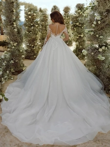 Detailed back view of a white lace wedding gown with pearl buttons and long cathedral train