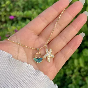 Close-up of gold beaded necklace with pearl starfish and blue crystal fish pendants
