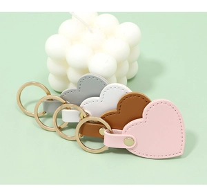 Close-up of heart-shaped leather keychains in various colors with golden key rings.