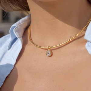 Primo piano di una collana a girocollo dorata con pendente in zircone a goccia