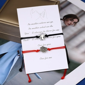 Close-up of handmade spider and web couple bracelets on a message card with poem