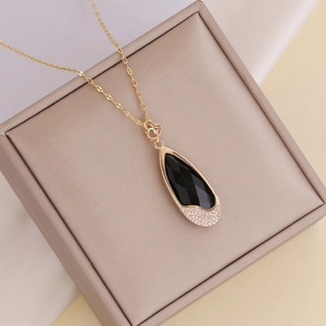 Gold chain necklace with black teardrop pendant featuring white crystals and heart detail