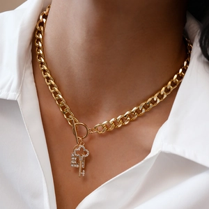 Close-up of gold Cuban chain necklace with sparkling crystal padlock and key charms