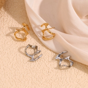 Détail de boucles d'oreilles géométriques creuses irrégulières en or et argent sur texture
