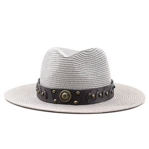 Detailed macro of woven straw hat featuring brown leather band and bronze rivets