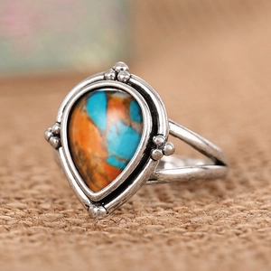 Gros plan sur une bague vintage en argent avec pierre multicolore en forme de goutte