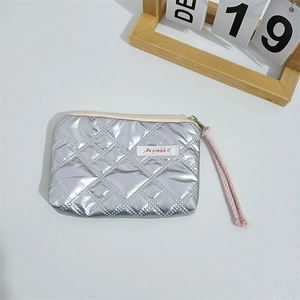 Macro view of silver quilted metallic heart coin purse featuring a Mayrabbit woven label