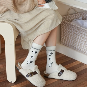 Detail of knit socks with sheep motif and 'I like counting sheep' text in a cozy setting