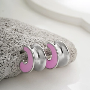 Detail view of C-shaped stainless steel earrings with pink enamel finish on natural grey stone