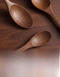 Close-up of three long-handled wooden spoons with natural dark grain on a wood background