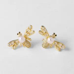 Detalle de pendientes de abeja dorados con perlas blancas y circonitas en micro-pavé