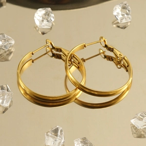 Polished 18k gold plated stainless steel hoop earrings on a reflective luxury background