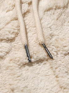 Macro shot of soft off-white fleece fabric texture and hoodie drawstring with metal tip