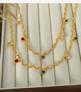 Detail of gold wave chain necklace featuring multi-colored heart-shaped zircon stones