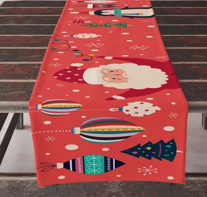 Detail of red Christmas table runner with Santa, penguin and snowflake prints on wood